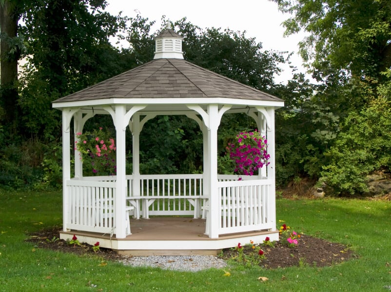 A lovely white gazebo with bench seating all around. This structure is an island in the sea of grass and the foliage behind it allows for some privacy from neighbors.
