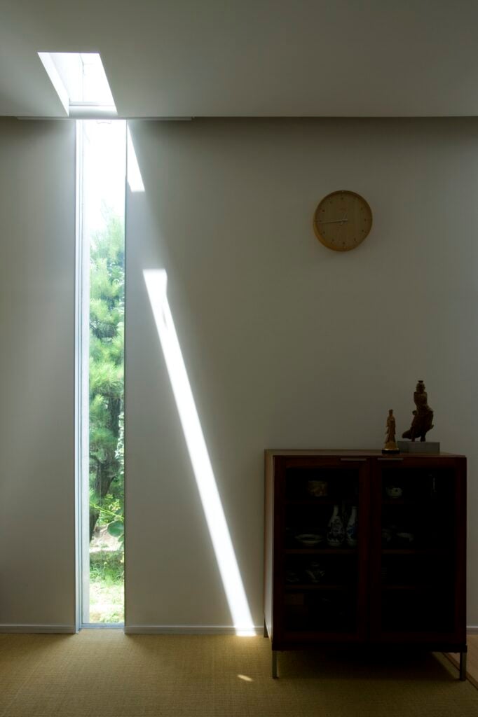 Here is a softer area of the home, with bamboo flooring and dark wood dresser standing near one of the slits in the home itself, filled with glass and cutting into the ceiling.