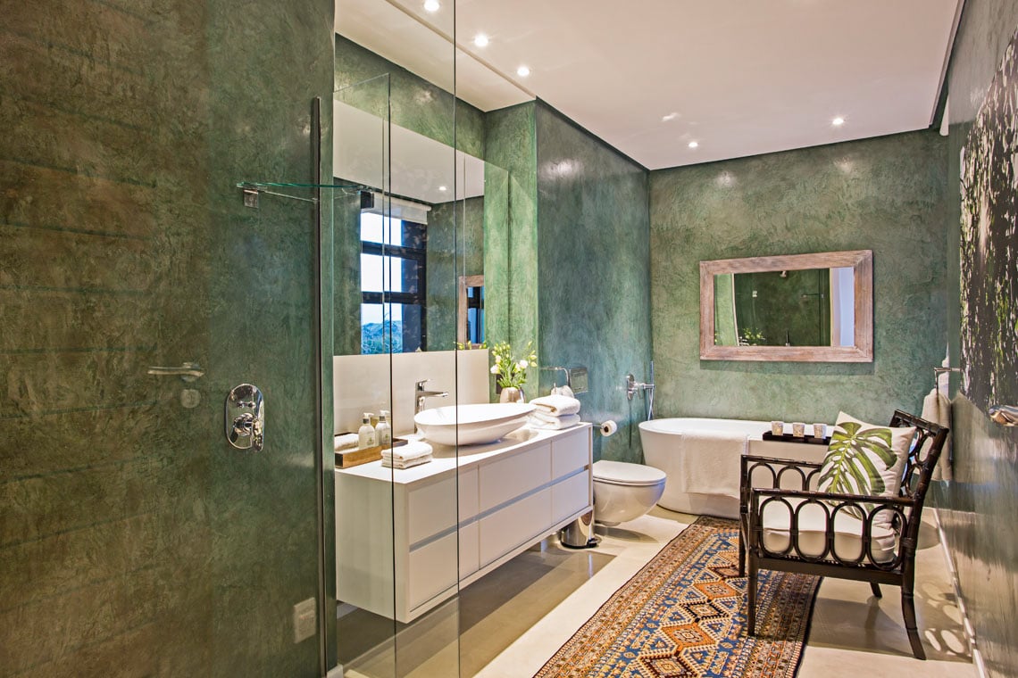 Marvelous bathroom features a forest green theme accented with a vintage runner. It includes a white floating vessel sink vanity and pedestal tub beneath a wooden framed mirror.
