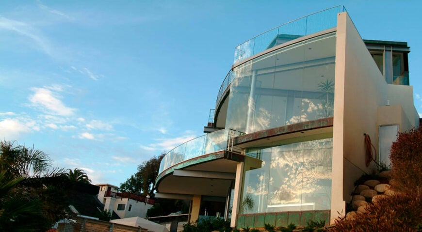 Exterior view of a cliff-top glass home overlooking the ocean designed by McClean Design