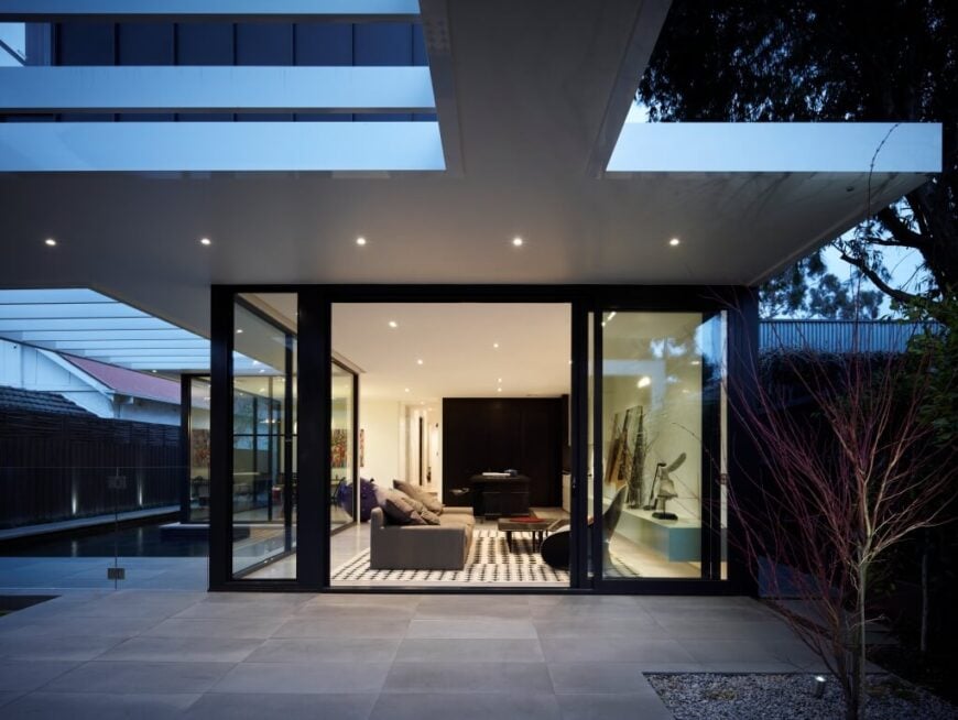 Viewed over the patio at night, we see the line between indoors and out blurred, with an oversized sliding glass door and recessed lighting continuing to the edges of the eaves.