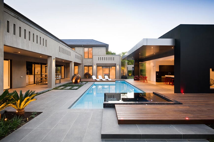 The pair of structures making up the estate meet at this central courtyard, filled with extraordinary details like the infinity-edge jacuzzi in the foreground, surrounded by bluestone and rich natural timber planks.