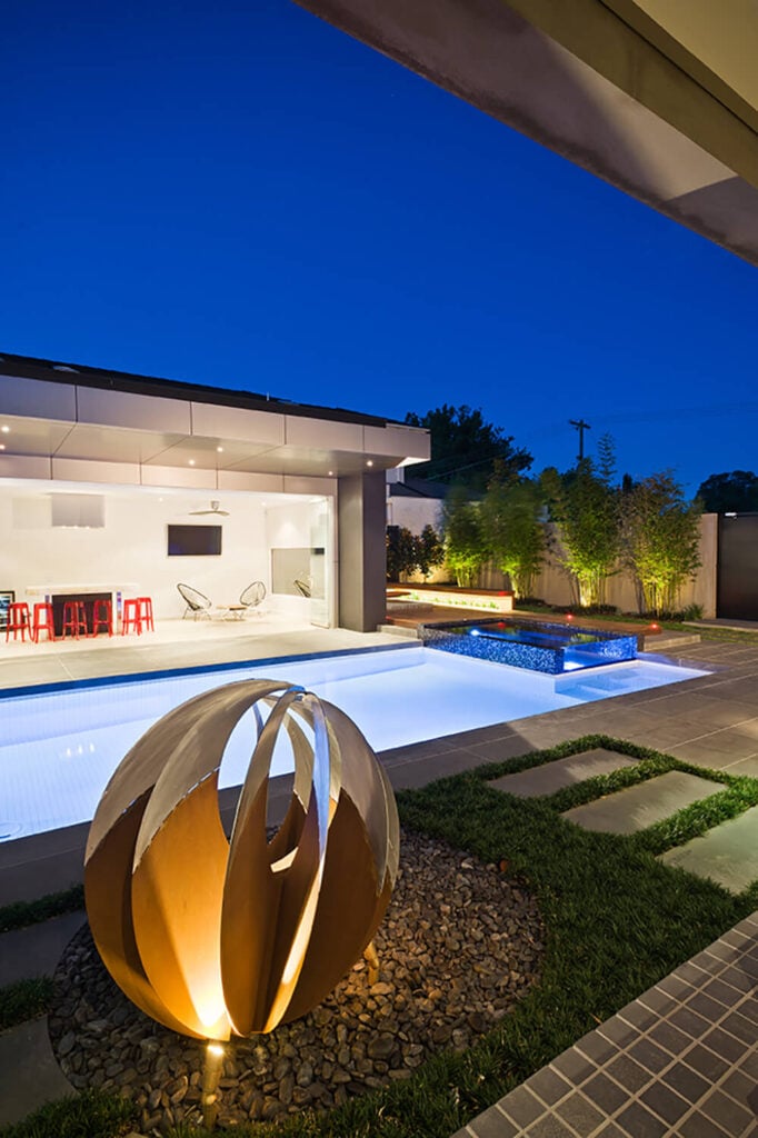 Here's a close look at the sculpture, settled on a bed of polished stones next to the pool. Across the water, we see the completely opened kitchen and relaxation space awash in white.