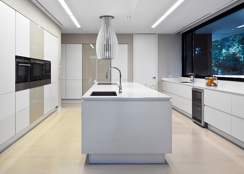 Modern kitchen featuring white kitchen counters and center island with white countertops, together with glass windows.