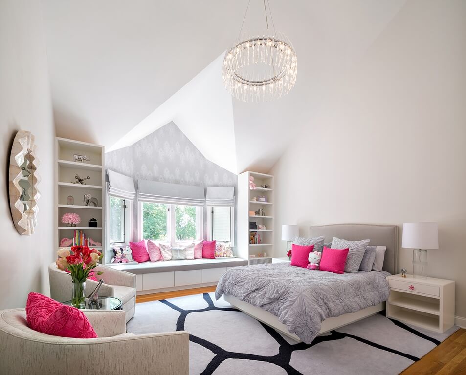 Large girl's bedroom with a large bed and a sun area with bench seating and multiple throw pillows. The rug looks classy while the seats look cozy.