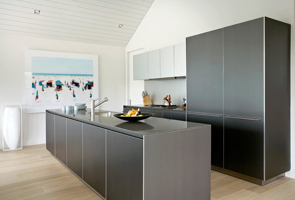 A modish kitchen with stylish kitchen counter and center island set on the hardwood flooring. The white walls feature a stylish wall decor.