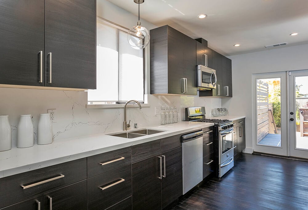 The espresso finished cabinetry and kitchen counters with white countertops look very elegant together with the hardwood flooring.