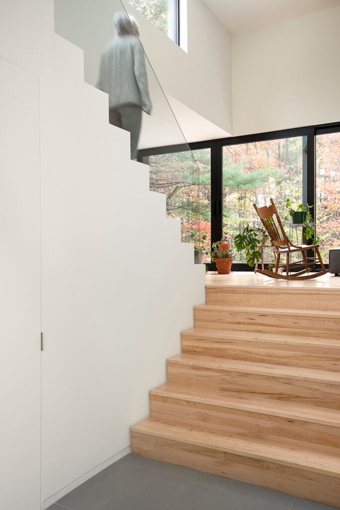 As we enter the home and start up the stairs, we are greeted by light wood grain steps and a wonderful view outside the window across the house. The high ceiling helps to really open up the space and welcome anyone who enters.