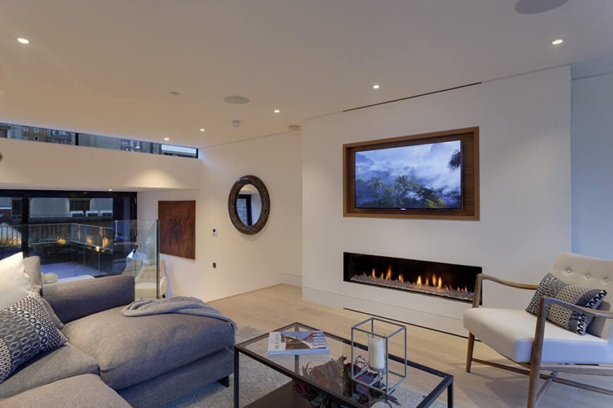 Moving up a floor, we see the distinctly layered construction of the house sprawling linearly between the narrow walls. In this living room area, contemporary furniture meets light hardwood flooring and spare placement of art objects.