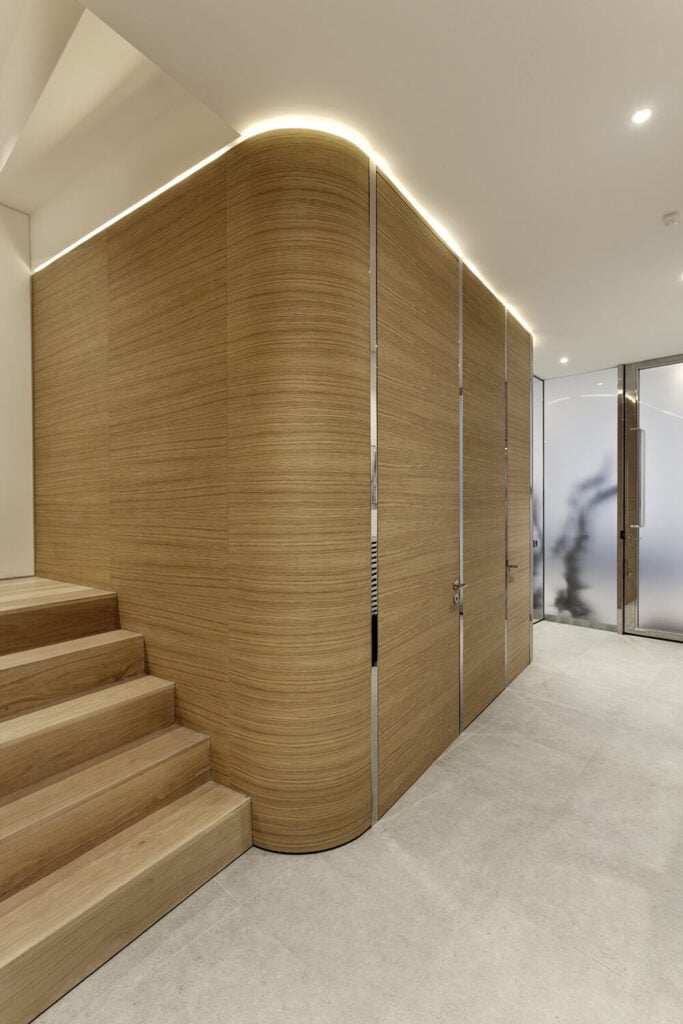 On the lower level, we see the light natural wood accents become a major force in the design, wrapping organically around the central elevator core.