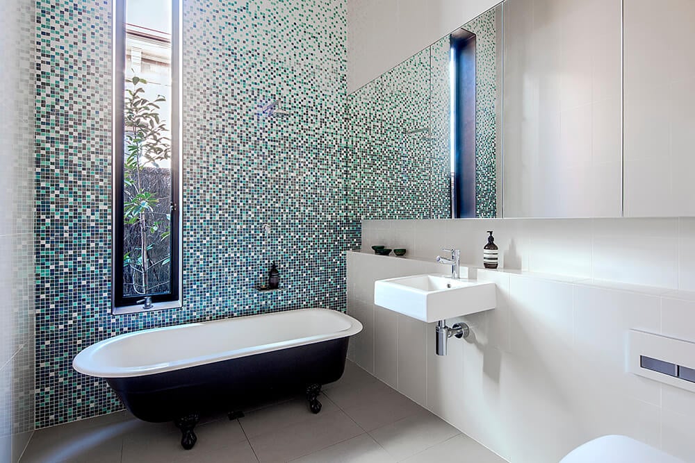 This bathroom features a very enchanting tiles wall near the freestanding tub. The floating vessel sink looks absolutely stunning as well.
