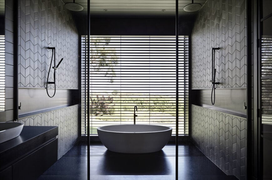 The primary bathroom centers on this huge bathing area, a small room within a room containing shower function and a bold white pedestal tub. The huge window provides exquisite views from the bath while shades keep privacy.
