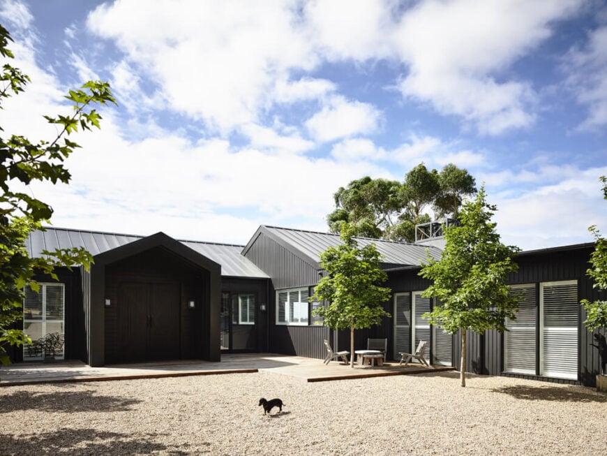 Approaching the home over the pebble driveway, we see a sprawling layout with multiple points of entry and large, full height windows carefully placed. The large double door entryway is framed with a deep overhang for protection from the elements.