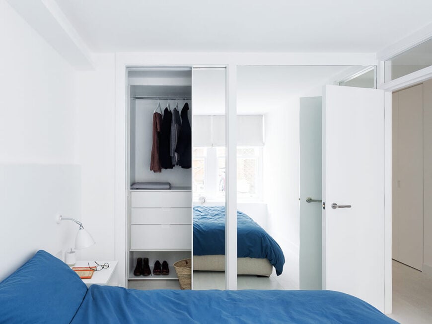 The bedroom makes use of large wall-size mirrors to help visually expand its size. A small window over the doorway extends the connectivity through to the rest of the home.