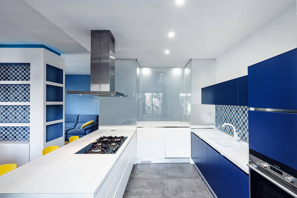 Stunning white kitchen with blue shade. The smooth countertops are just perfect together with the recessed ceiling lights.
