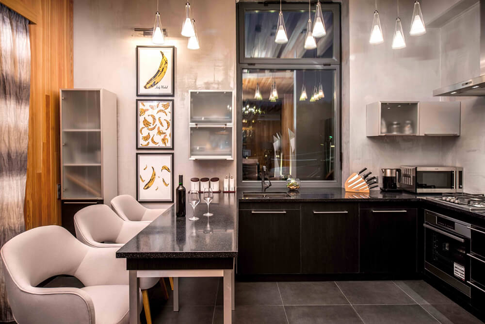 This kitchen features black finished counters equipped with granite countertops. The pendant lights look absolutely stunning.