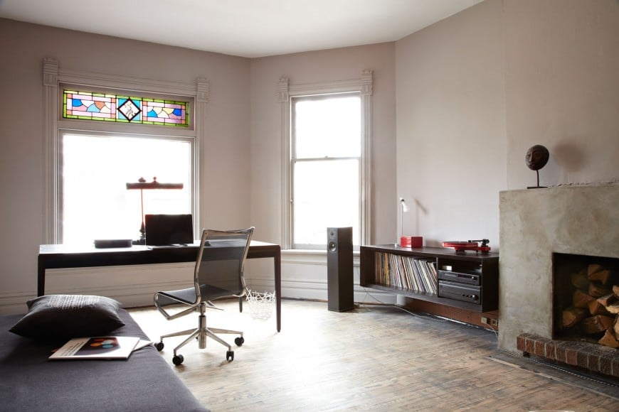 Rustic bedroom features a home office by the window fitted with lovely stained glass. It has a dark wood office desk paired with a mesh office chair.