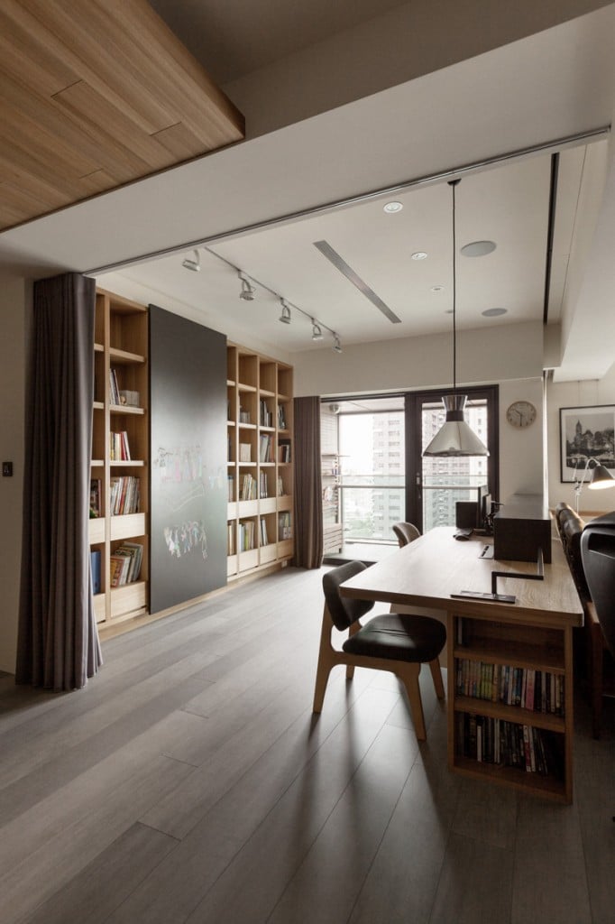 A chrome pendant illuminates this home office along with recessed and track lights fixed on the white ceiling. It has a natural wood desk fitted with built-in shelves.