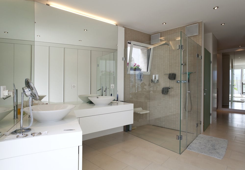 Primary bathroom features an L-shaped floating vanity with dual vessel sink and frameless mirror. It has a walk-in shower with subway tiles backsplash.