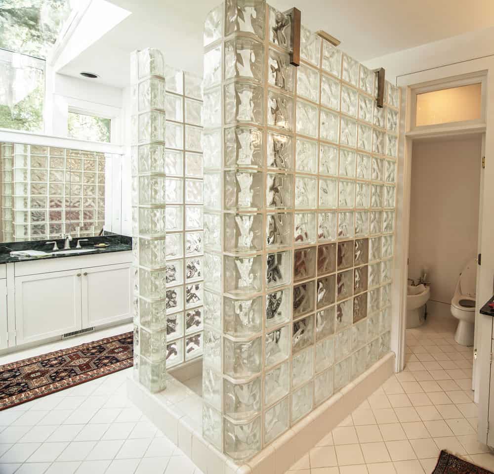 This primary bathroom offers a classy walk-in shower and a sink counter with an elegant black marble countertop.