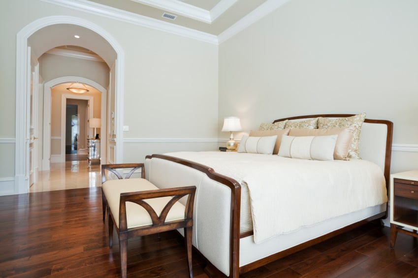 This primary bedroom features a light-finished walls. The hardwood flooring matches the bed's frame.