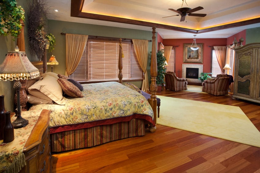Large primary bedroom featuring a hardwood flooring and green walls. There's a fireplace with a couple of club chairs. The ceiling looks great.