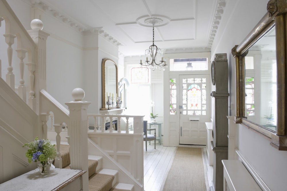 This home features a foyer with white walls and a lovely white ceiling. The area has a sitting area on the side featuring a fireplace, lighted by a chandelier.