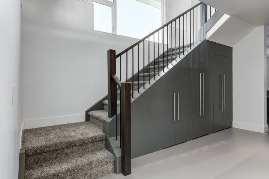 Modish staircase with gray carpet floors and white walls.