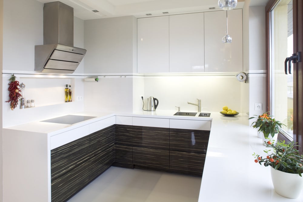This kitchen features white cabinetry, walls and smooth white countertops.