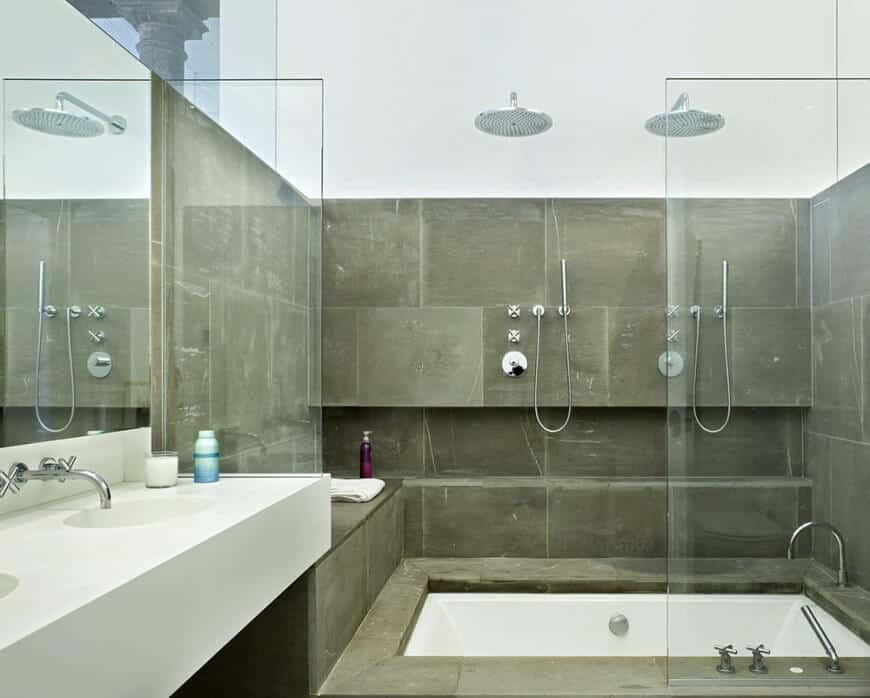 Natural stone tiles wall filled this contemporary bathroom. It has a tub and shower combination framed with glass and a floating vanity sink next to it.