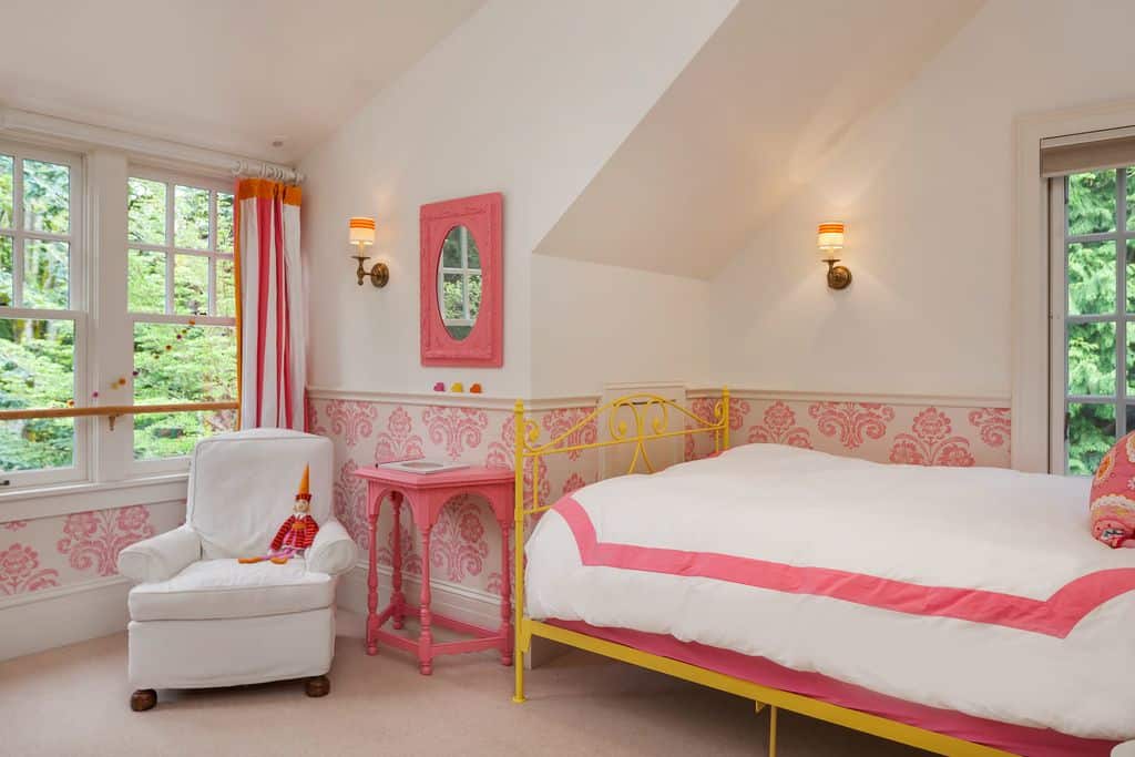 This girl's bedroom features nice walls with pink accent, lighted by classy wall lights.