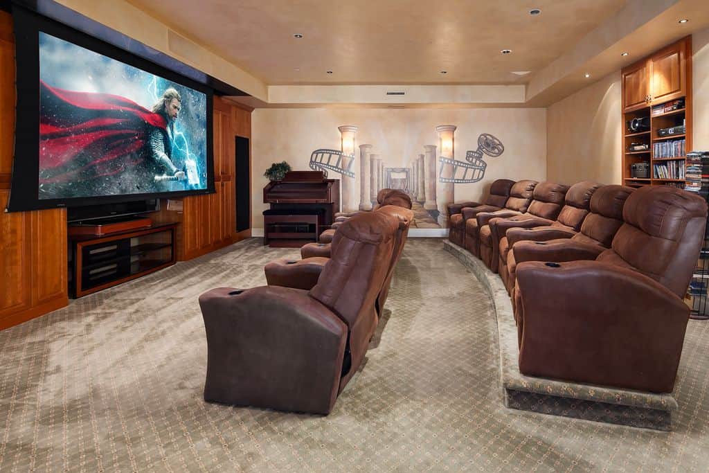 A large home theater featuring sectional theater seats on top of the classy carpet flooring.