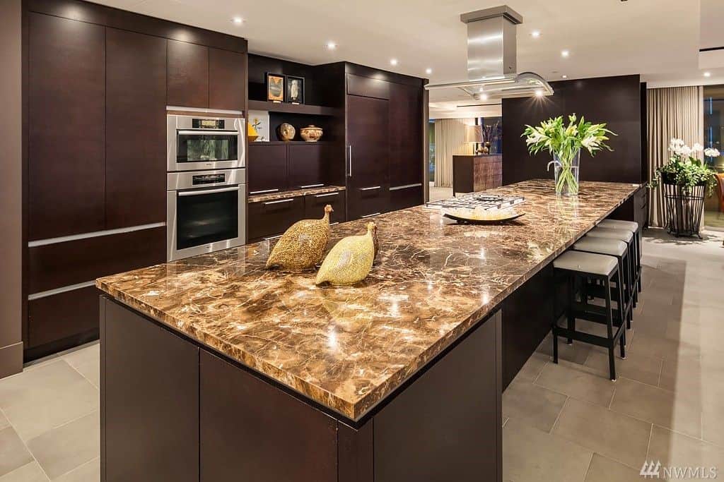 This kitchen boasts elegant counters and cabinetry, along with a massive center island featuring a very charming countertop.