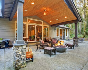 large back yard with grass and covered patio with fire pit