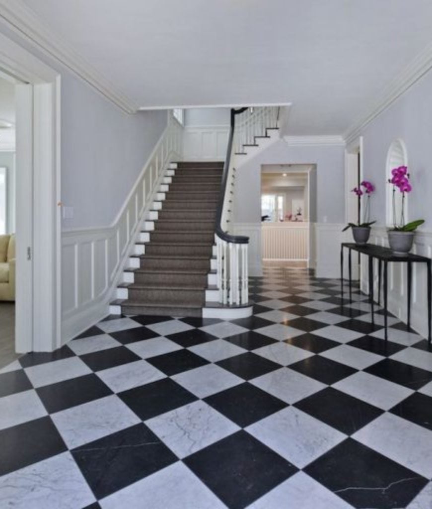 Kyle Richards And Mauricio Umansky's entryway's laminated classic black and white checkered flooring looks perfect and compliments the brown stairs that leads to the second floor.