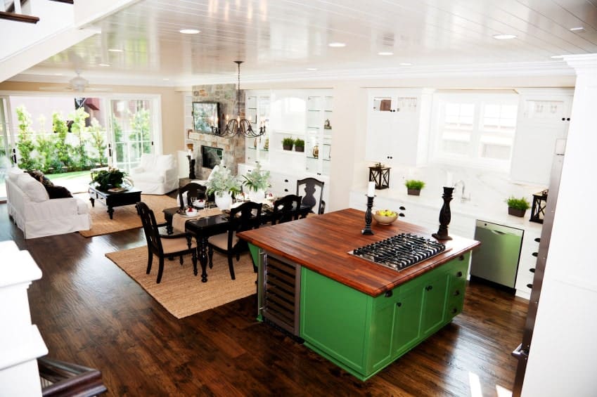 The highlight of this Tropical-style kitchen is the bright green kitchen island with a redwood countertop that matches with the hardwood flooring. The peninsula is almost washed out by the brightness of the window that is augmented by the white ceiling and white countertop.