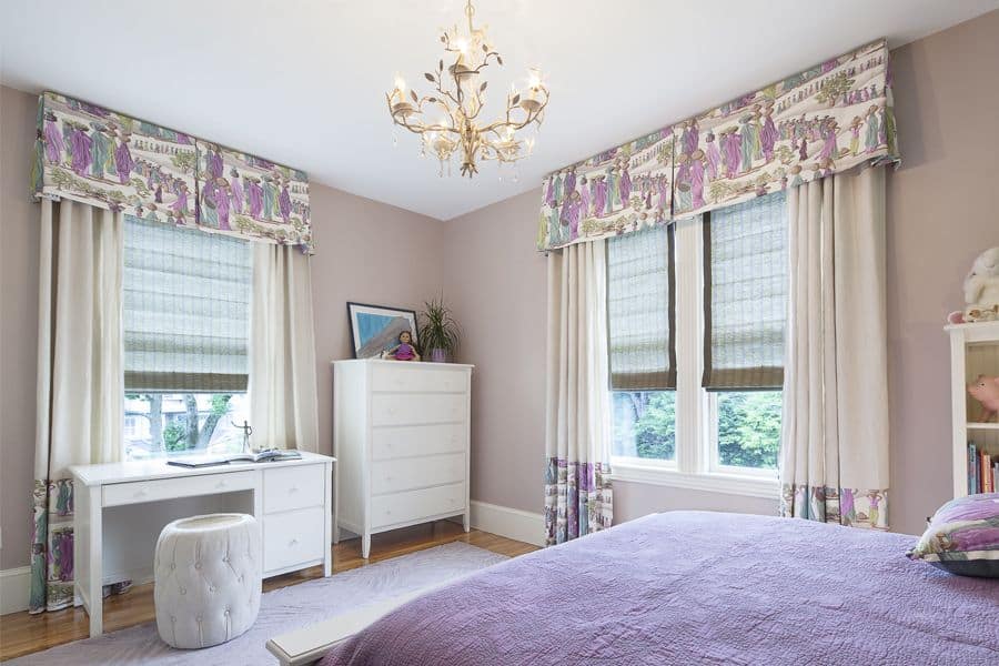 This girl's bedroom offers a large bed and a small desk lighted by a glamorous chandelier. The purple accent looks stylish as well.