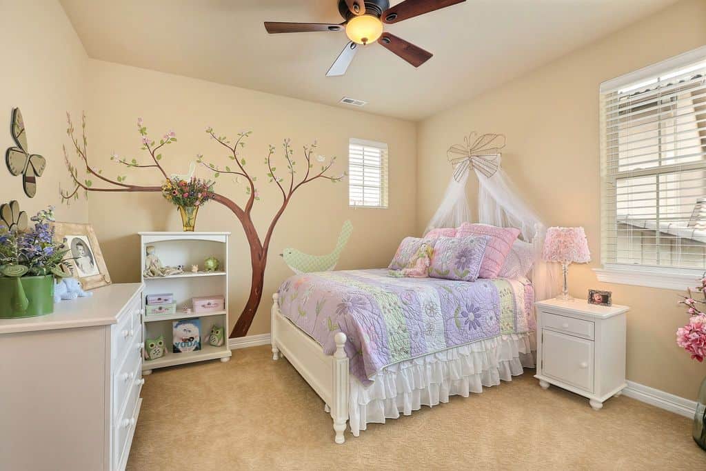 Small girl's bedroom featuring an interesting wall design on the beige walls matching the carpet flooring.