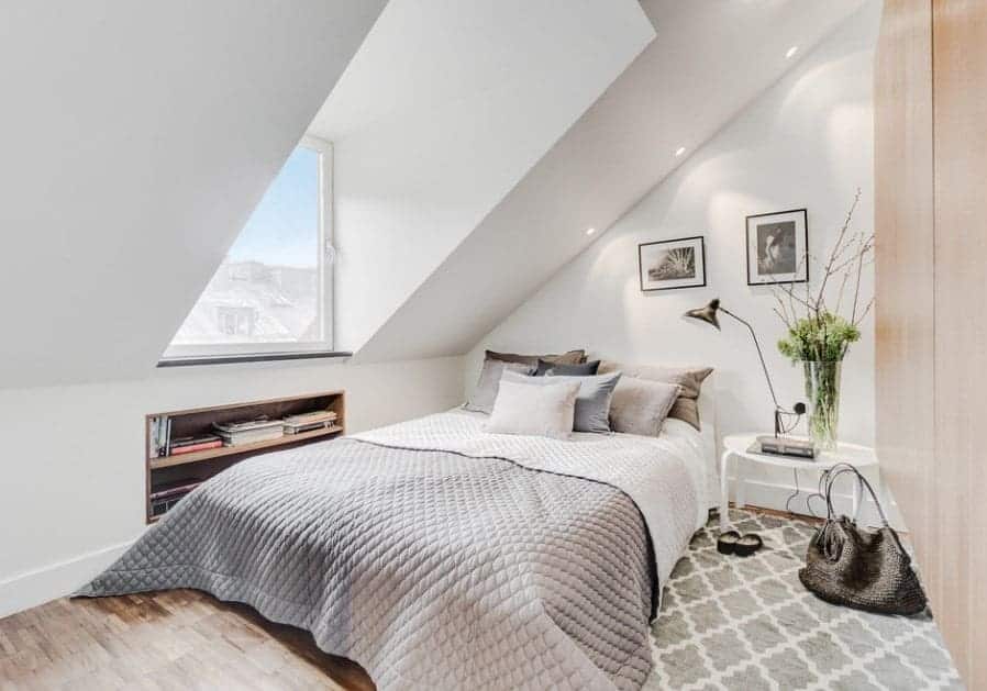 Small Scandinavian-Style primary bedroom featuring a shed ceiling and stylish hardwood flooring topped by a rug.