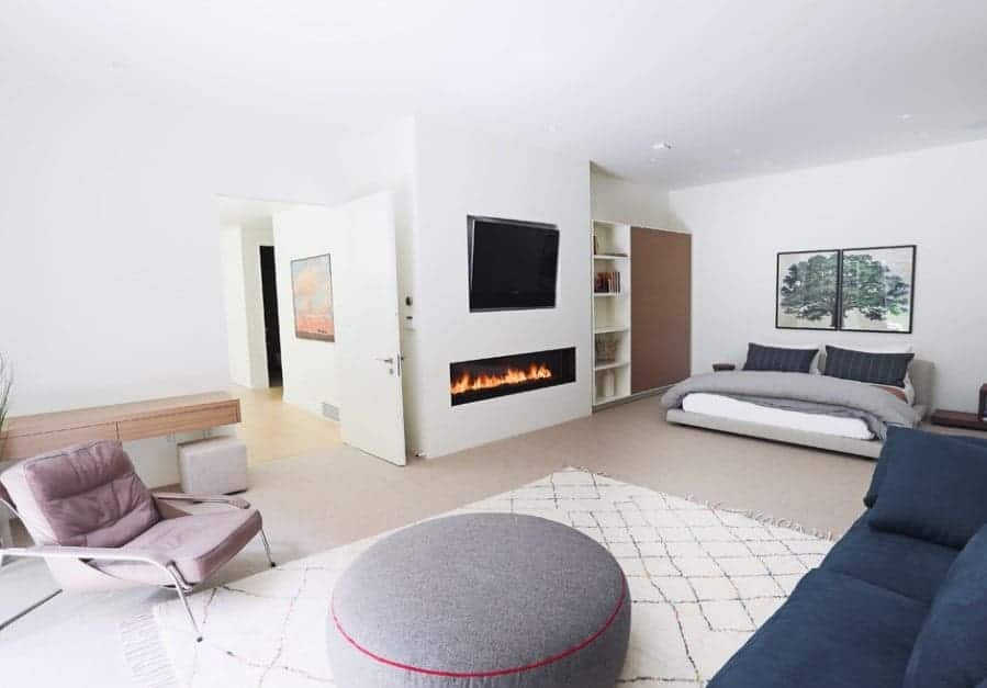 A modish Scandinavian-Style primary bedroom with its own living space offering cozy seats and a fireplace.