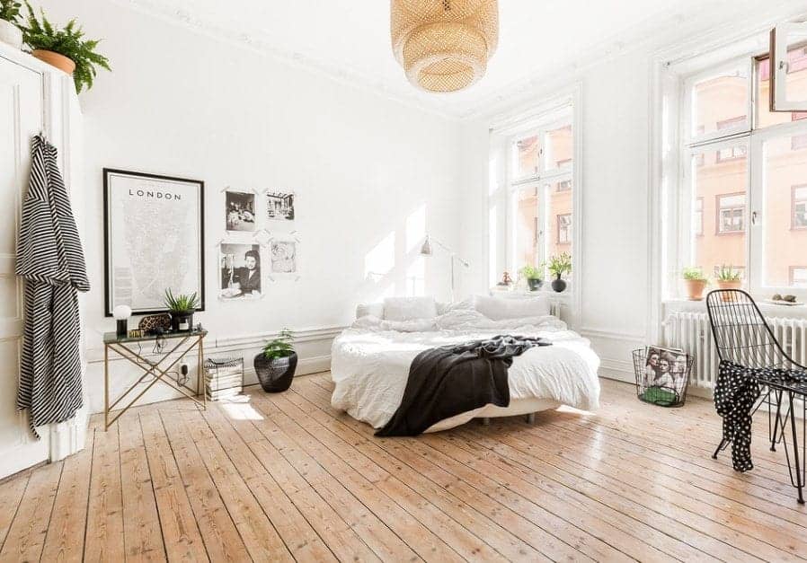 Large Scandinavian-Style primary bedroom featuring white walls and ceiling and hardwood flooring. The bed looks very romantic.