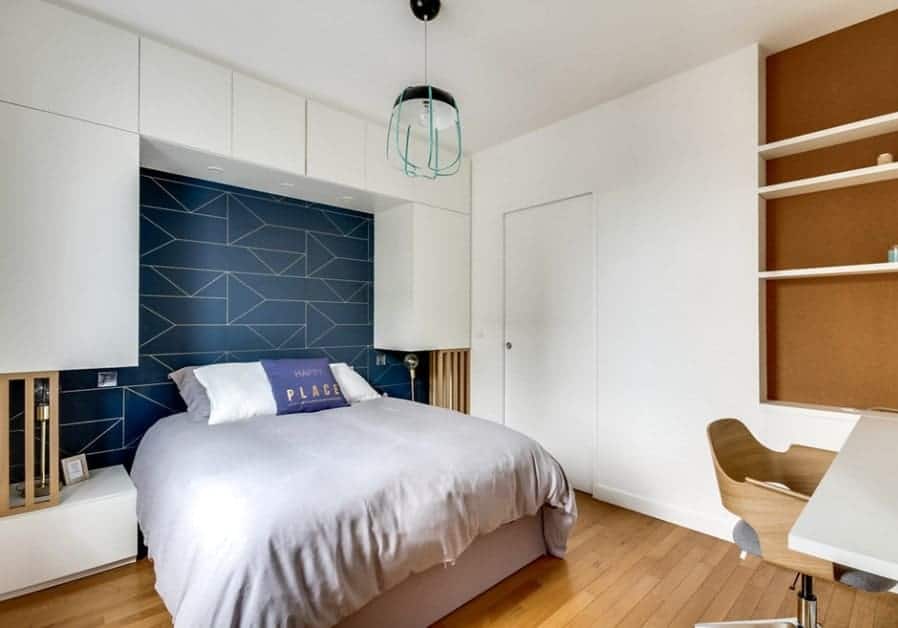 A modish Scandinavian-Style primary bedroom with a stylish wall and a small study desk with multiple shelves on the wall.