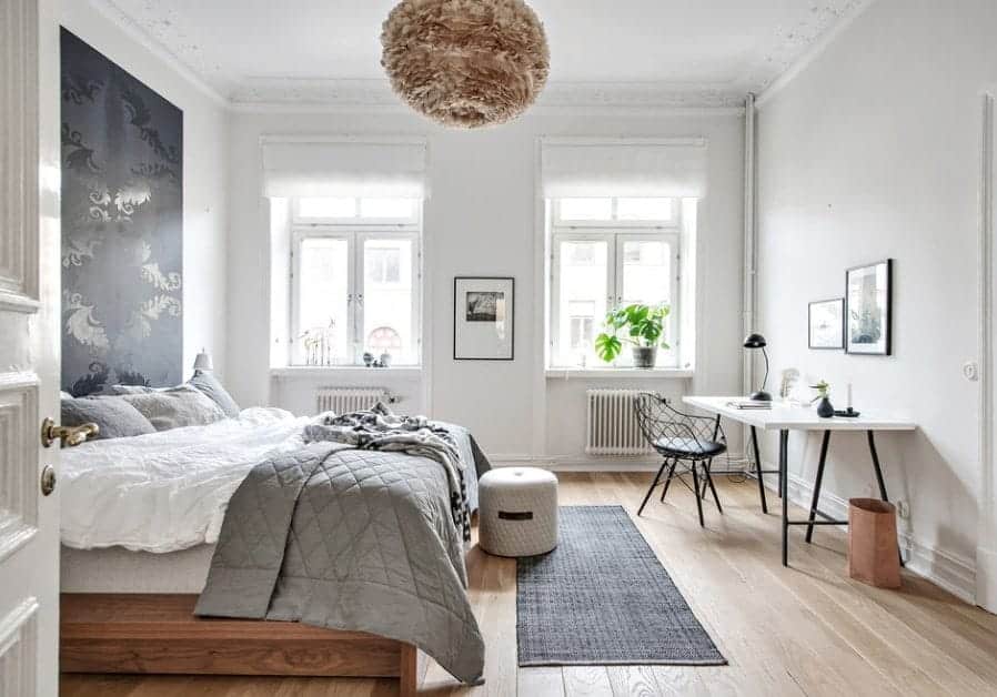 This Scandinavian-Style primary bedroom features a stylish wall design and a study desk on the side. The room also features hardwood flooring.