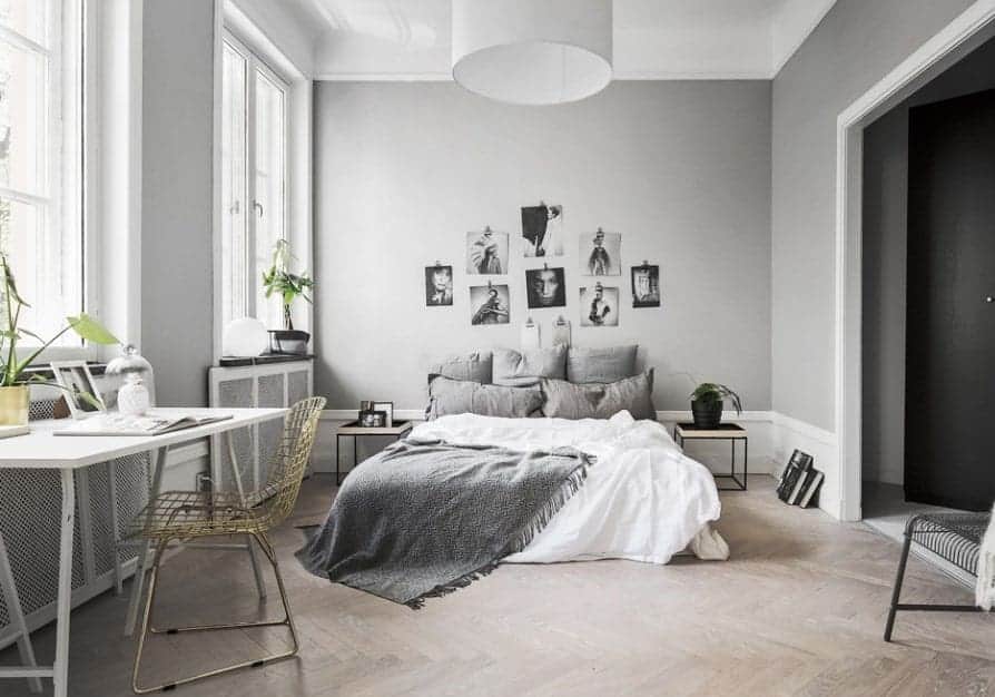 Large Scandinavian-Style primary bedroom featuring stylish gray walls with attractive wall decors and herringbone hardwood flooring.