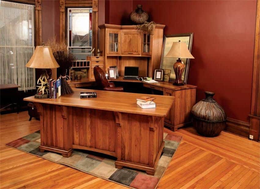 Craftsman home office with curved and wooden desks that sit on a checkered rug over hardwood flooring. It includes table lamps and antique jars.