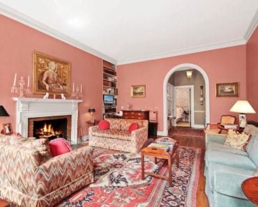 Large Traditional living room with pink walls, arched doorway and a brick fireplace.