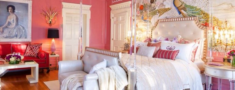 Elegant pink master bedroom with chandelier table lamps, accent chairs and a large artwork behind the posh four poster bed.