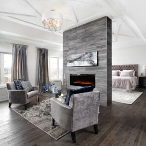 Transitional primary bedroom with hardwood floor and grey accent chairs.