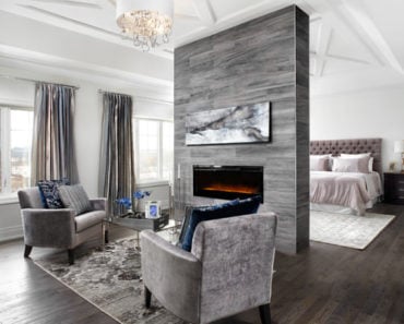 Transitional master bedroom with hardwood floor and grey accent chairs.