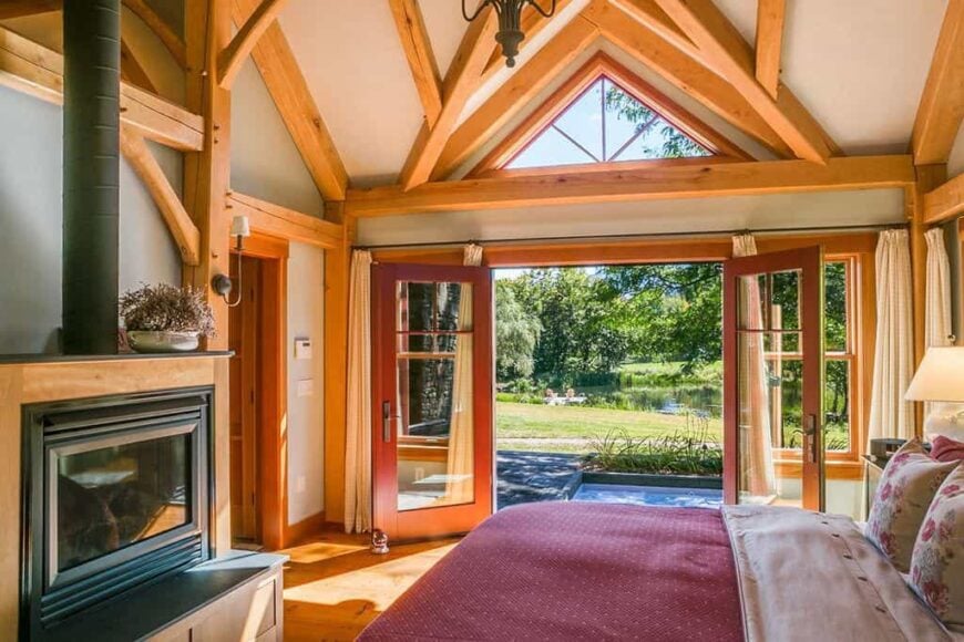 Wonderful wood beams and double door entry lead the eye to a picturesque view from this mid-size craftsman primary bedroom.